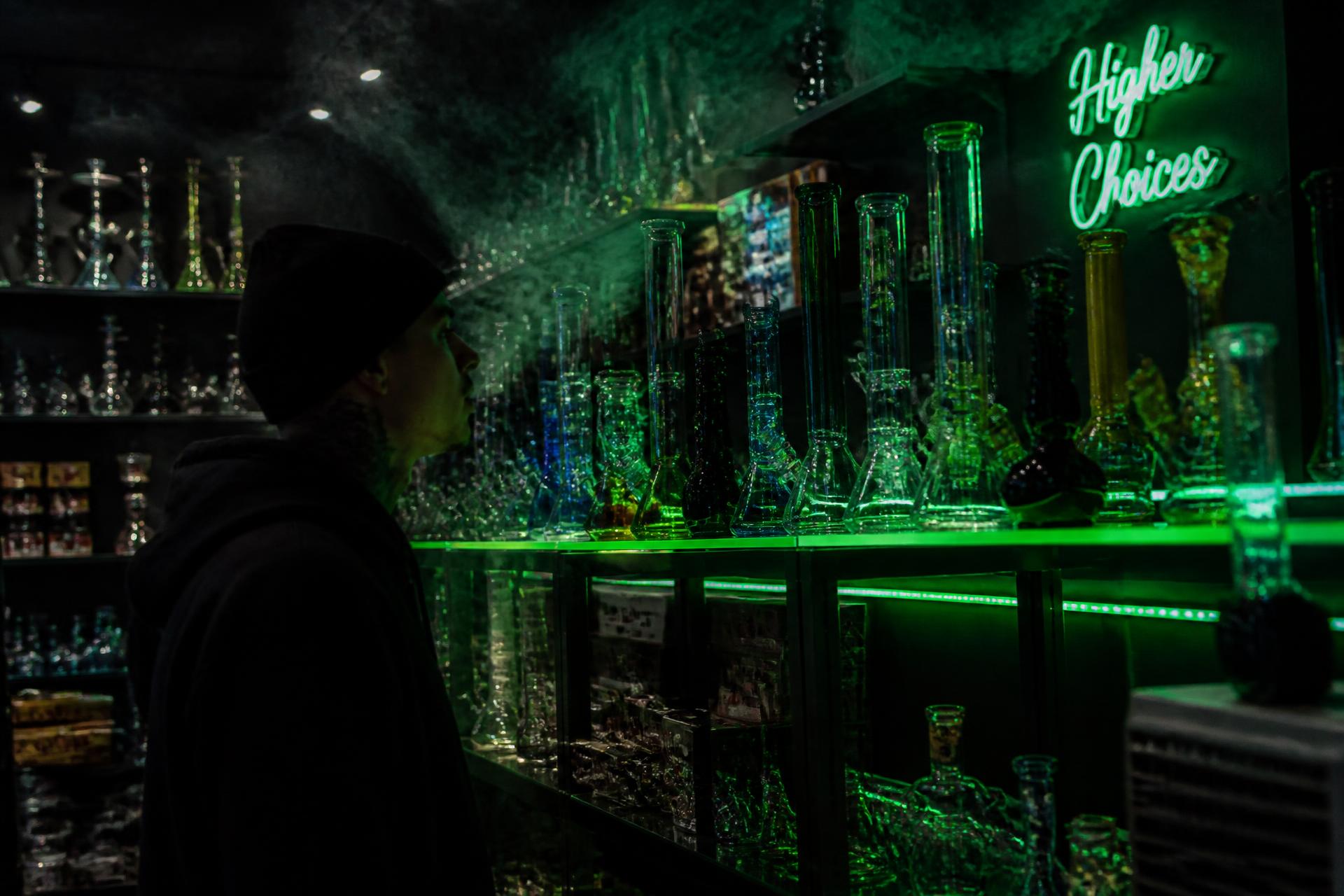 Shelves of glass water pipes glowing under neon light inside Smokey's Smokeshop