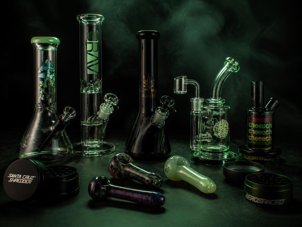 Glass bongs, spoon pipes, a dab rig and grinders on a dark surface